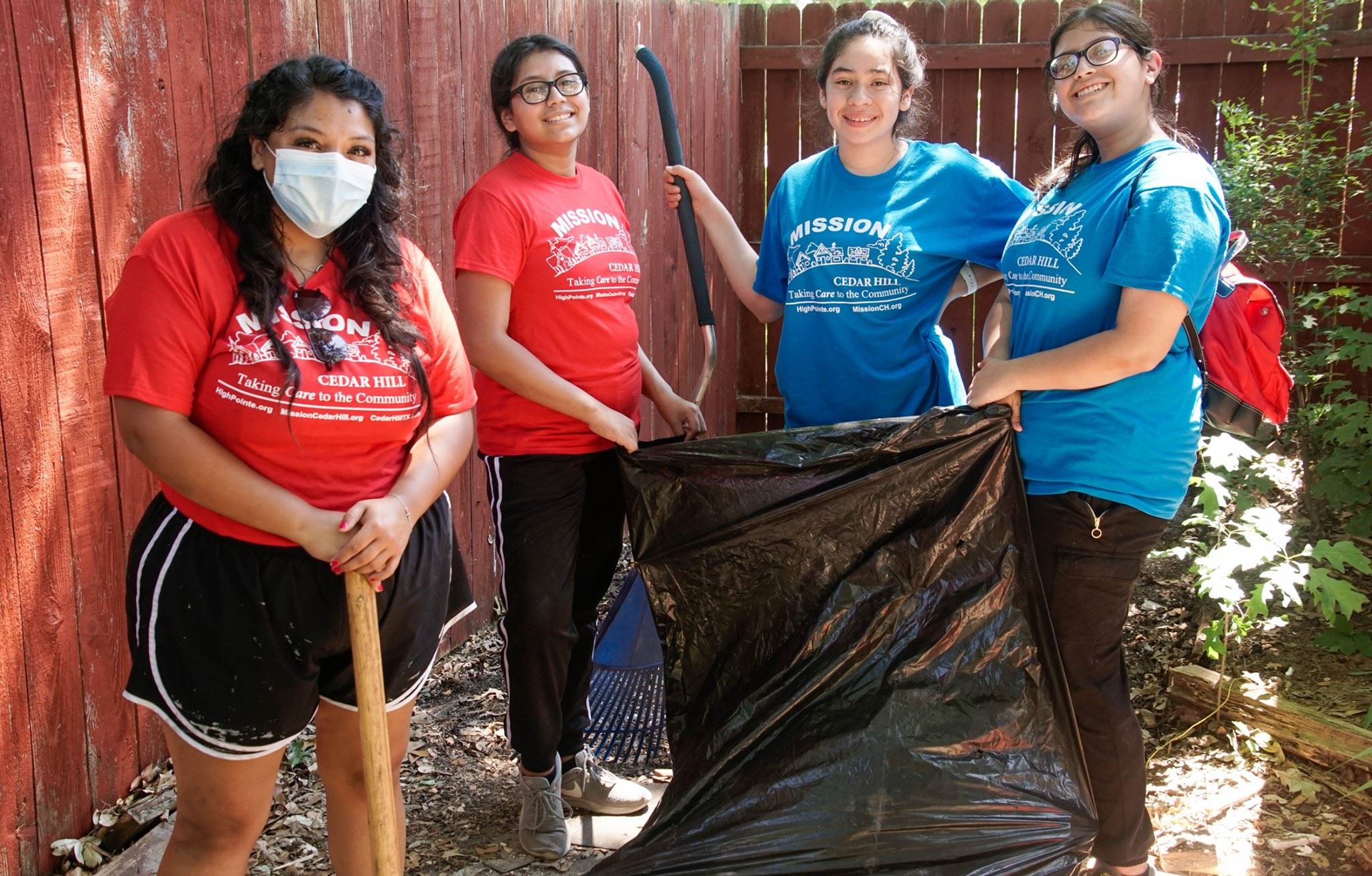 A group of young people in blue and red shirts clearing brush